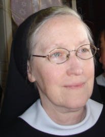 A nun with wire glasses looks off to the right