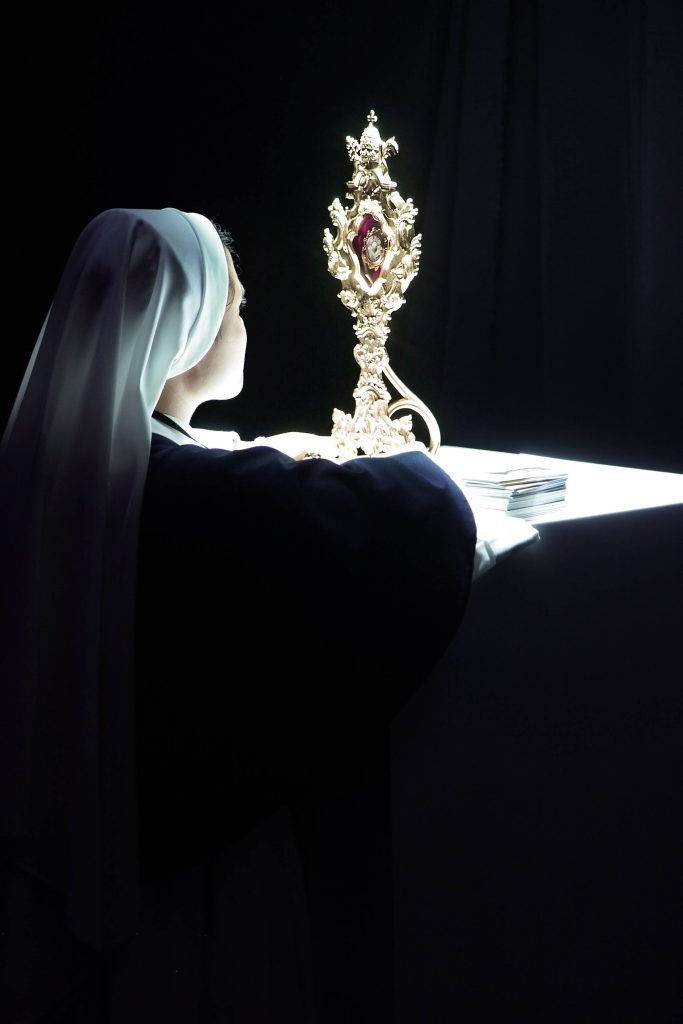 a nun kneeling before a reliquary