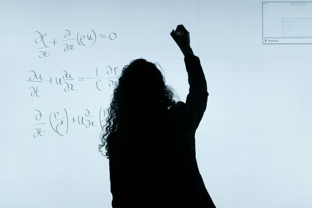 silhouette of a woman writing math equations on a whiteboard