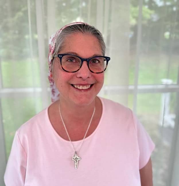 An older woman in a kerchief and pink shirt with glasses