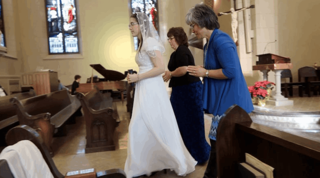 a bride walks down the aisle with two attendants