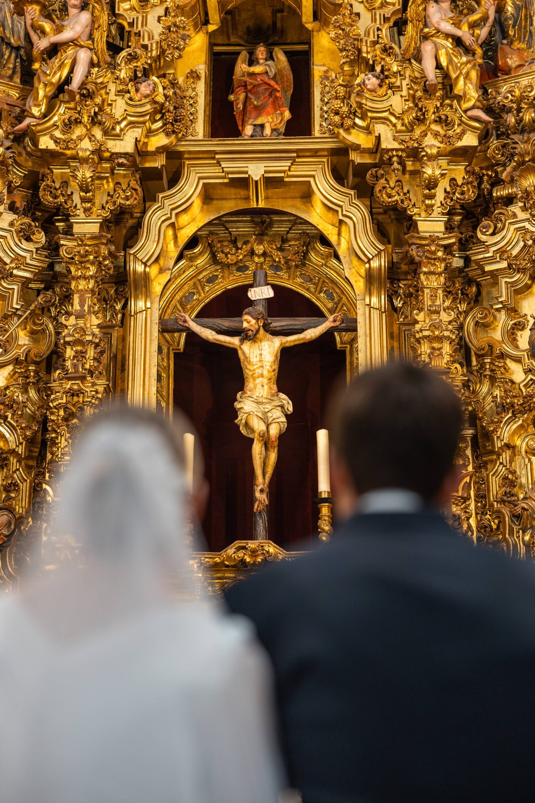 Jesus on the Cross in a golden chapel with a bridal couple facing him