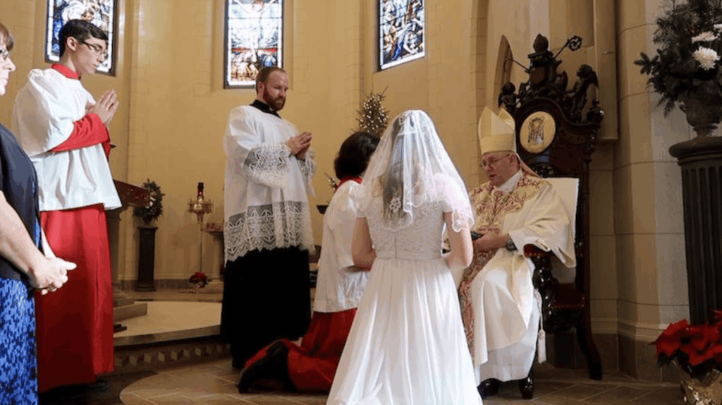 A bride of Christ kneels before the bishop for consecration