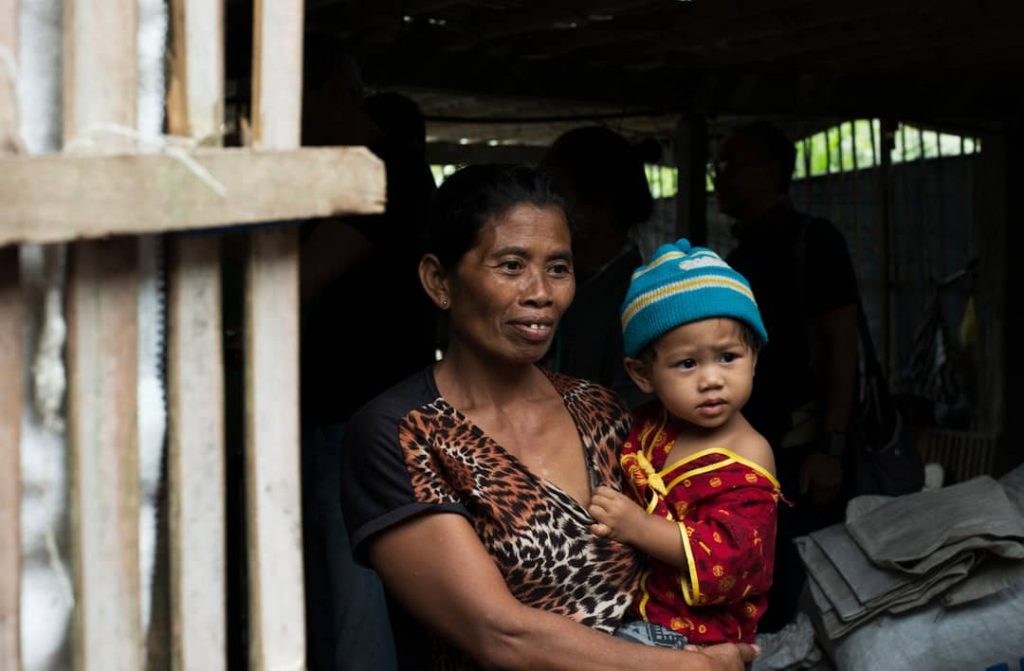 a woman holds her child in a hut