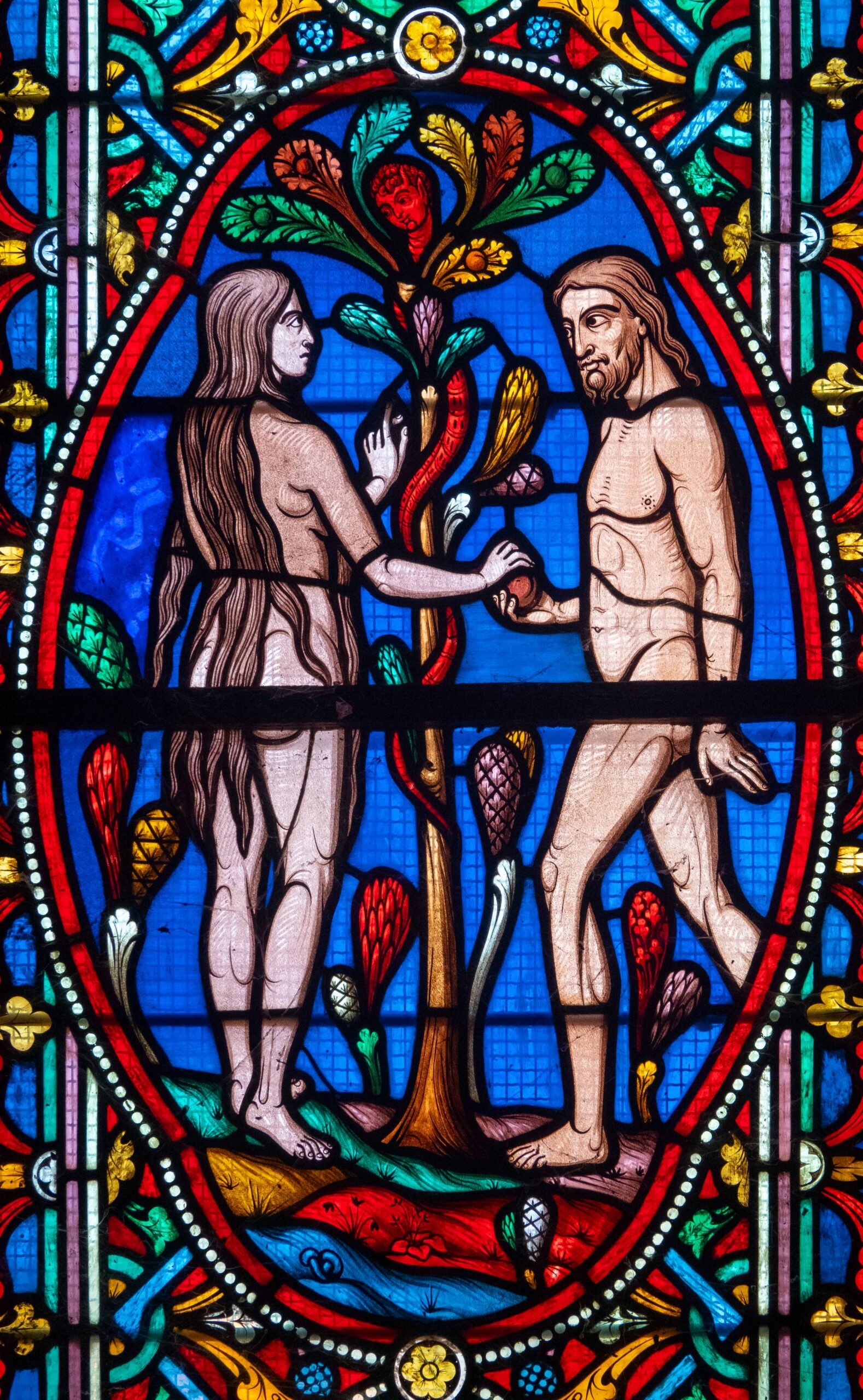 a stained glass of adam and eve and the apple and the serpent