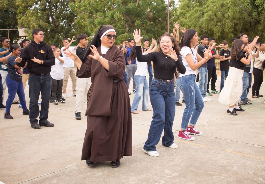 a nun in a brown habit dances with young adults
