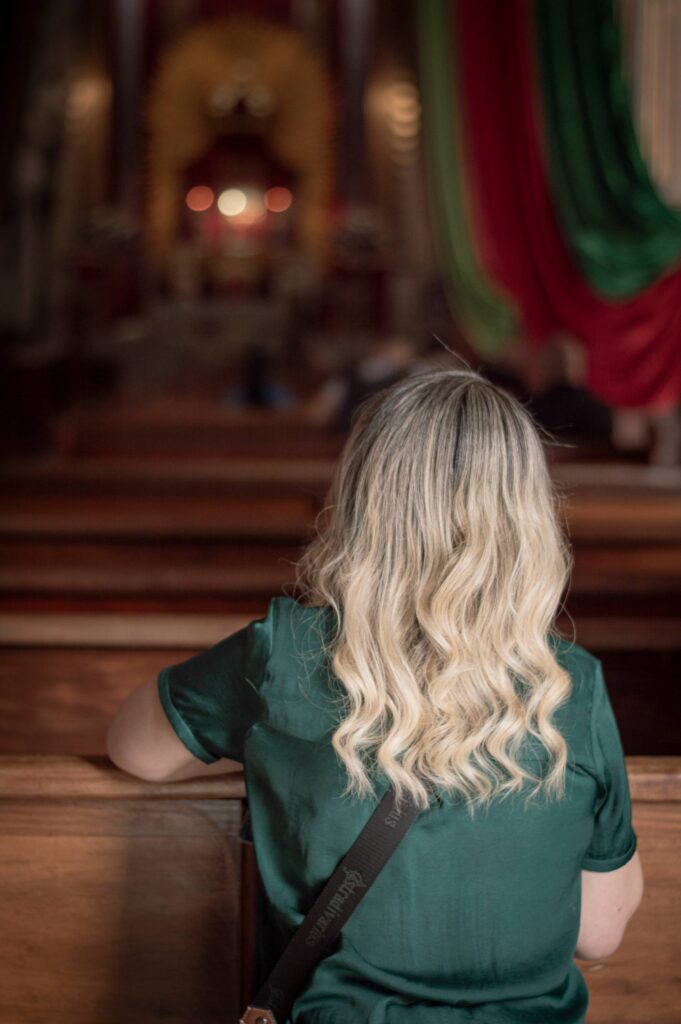 a woman in a pew praying with a green shirt and blond hair