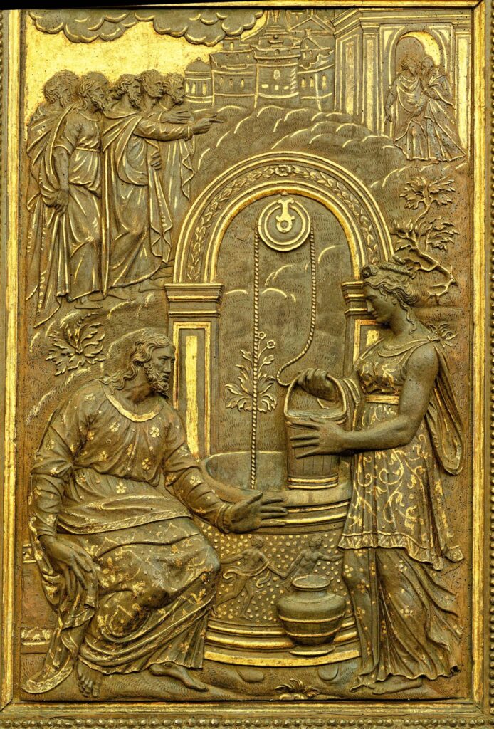 A gold relief sculpture showing a woman at the well with jesus